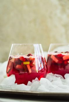 two glasses filled with liquid sitting on top of ice covered trays next to each other