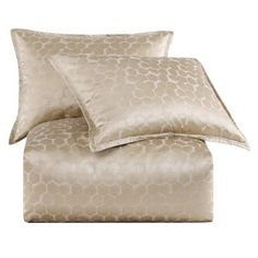 a bed with two pillows and one pillow on top of the covers in gold color