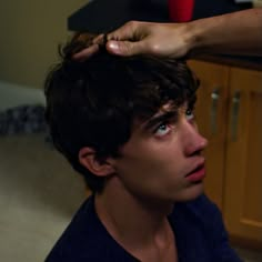 a young man getting his hair cut by someone