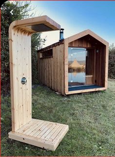 a wooden structure with a glass door in the grass