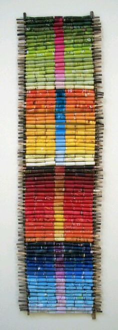 an art piece made out of colored pencils on a white wall next to a painting