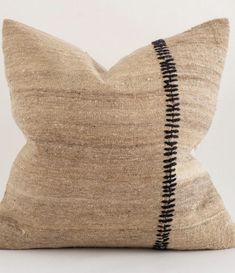 a beige pillow with black zippers on the front and back, sitting on a white surface