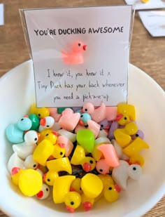 a bowl full of rubber ducks sitting on top of a table next to a sign