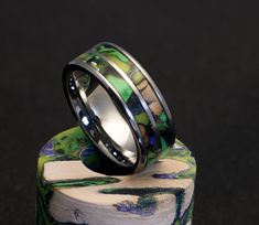 two rings sitting on top of each other in front of a wooden stand with black and green designs