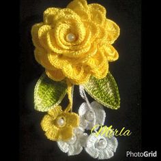 a crocheted yellow rose with leaves and pearls