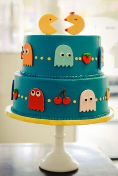 a three layer cake decorated with pacman and ghost characters on it's sides