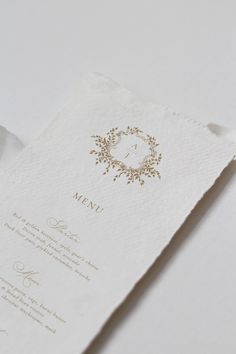 a close up of a menu on a white table cloth with a gold frame and floral design