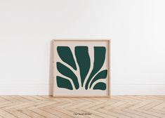 a wooden frame sitting on the floor in front of a white wall with a green print