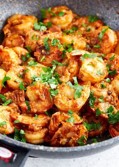 a skillet filled with cooked shrimp and garnished with parsley