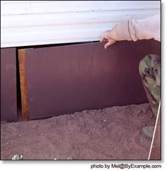 a person kneeling in the sand with their hand on the ground next to a building