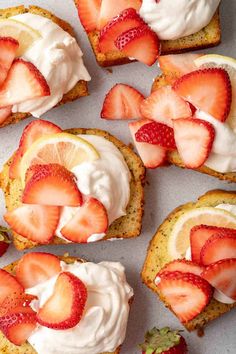 strawberry shortcakes with whipped cream and sliced strawberries on top, sitting on a baking sheet