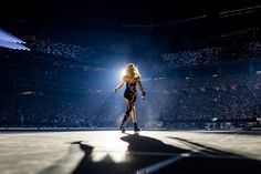 a woman standing on top of a stage in front of a crowd at a concert