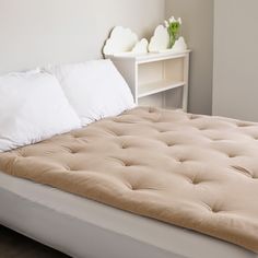 a bed with two white pillows on it and a shelf in the corner behind it