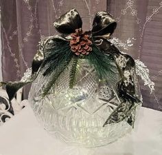 a clear glass vase filled with pine cones and bows