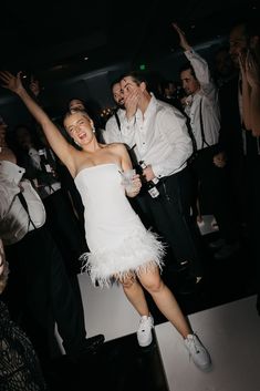 a woman in a white dress is dancing on the dance floor with her arms up