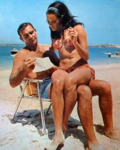 a man and woman sitting on the beach