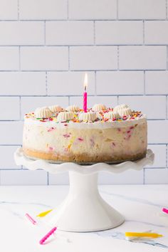 a birthday cake with white frosting and colorful sprinkles on a pedestal