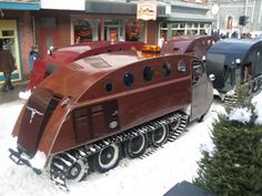 a train that is sitting in the snow next to some trees and people walking around