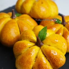 small oranges are arranged on a black plate with green leaves in the top corner