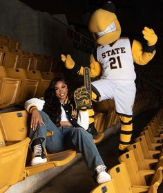 a woman sitting in the bleachers with a mascot