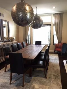 the dining room table is surrounded by black leather chairs and chrome balls hanging from the ceiling