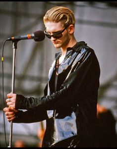 a man with sunglasses on his head holding a microphone in front of a microphone stand