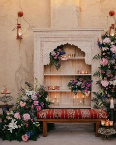 a room filled with lots of flowers and candles next to a book shelf covered in greenery