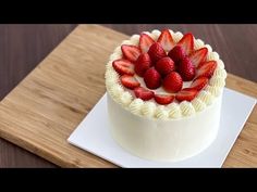 a cake with strawberries on top sitting on a cutting board next to a knife