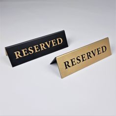 two black and gold reserved signs sitting next to each other