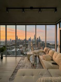 a living room filled with furniture and large windows overlooking the cityscape at sunset