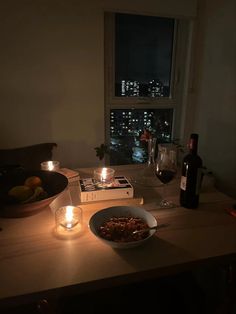 a bowl of food and some candles on a table with a window in the background