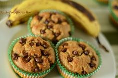 four chocolate chip muffins on a plate next to a bunch of ripe bananas