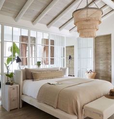 a bedroom with white walls and wood flooring has a large bed in the center