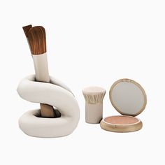 an assortment of cosmetics and makeup products on a white surface with one brush in the middle