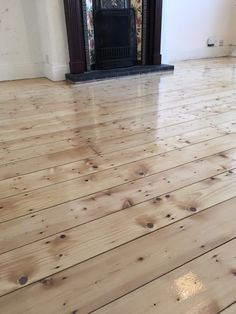 an empty room with wood floors and a fireplace