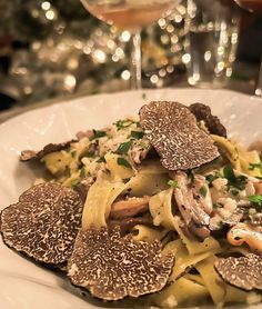 pasta with mushrooms and parmesan cheese on a plate next to a glass of wine