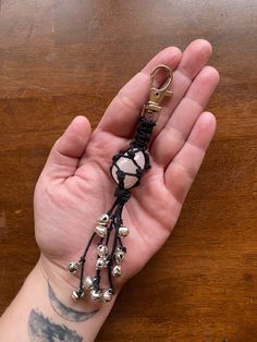 a person's hand holding a tassel with bells on it