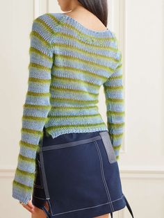 a woman wearing a green and blue sweater