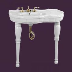 a white sink with two faucets on it's sides and gold handles