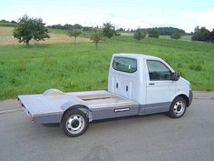 a white truck parked on the side of a road next to a lush green field