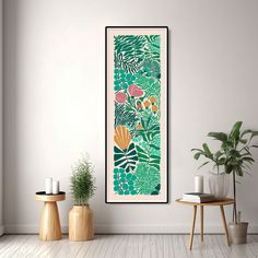 an art print hangs on the wall next to two potted plants and a small table