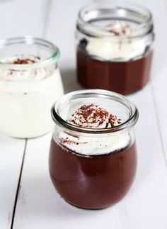 three jars filled with chocolate pudding on top of a white wooden table next to each other