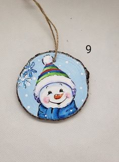 a wooden ornament with a snowman on it's face hanging from a string