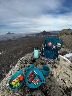 a backpack and two plates of food on top of a mountain