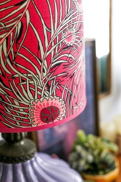 a lamp that is on top of a table next to a bowl and potted plant