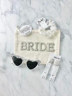 the bride sunglasses and bridal garter are laid out on a marble surface