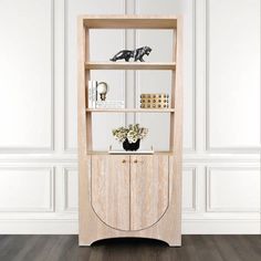 a wooden bookcase with plants and pictures on it in front of a white wall