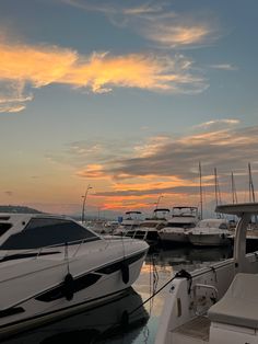 many boats are docked in the water near each other at sunset or sunrise, and one boat is white with black trim