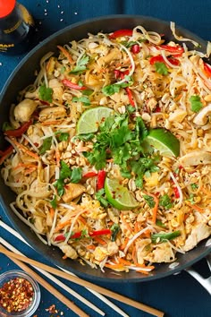 a wok filled with rice and vegetables on top of a blue table next to chopsticks