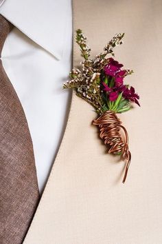 a boutonniere with purple flowers attached to the lapel of a man